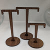 Three wooden earring stands on a white surface with a neutral background