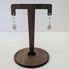 Wooden earring stand with two silver earrings on a white background